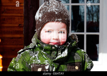 Portrait eines 2 Jahre alten Jungen mit Schnee bedeckt im Winter in Québec Stockfoto