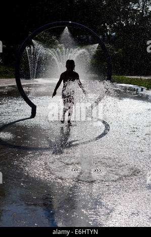 Ein junges Mädchen spielen im Wasserbrunnen an einem heißen Sommertag Stockfoto