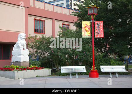 Das Calgary Chinese Cultural Center mit einer Außenansicht mit Lampe, Bänken und einer Löwenstatue in Chinatown, Kanada Stockfoto