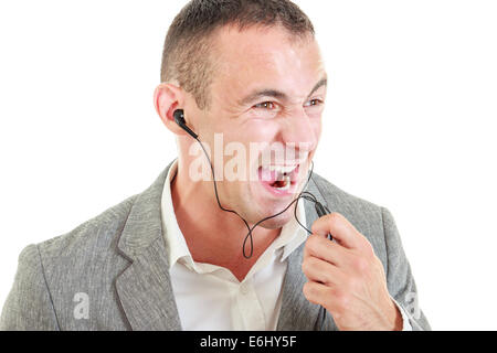 Verärgerter Mann mit Ohrhörer angeschlossen auf Mobiltelefon während des Gesprächs über Telefon Mikrofon schreien Stockfoto
