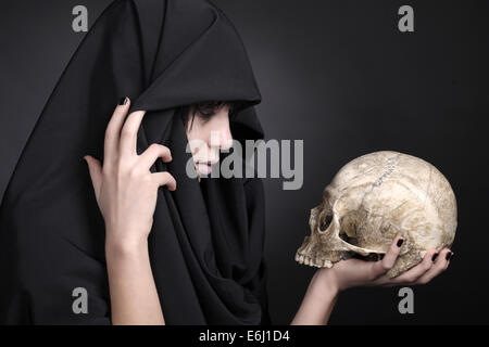 Frau mit einem menschlichen Schädel. Mit schwarzem Tuch bedeckt. Stockfoto