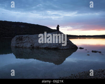 Lac de Chalain Sonnenuntergang, Jura, Frankreich mit Silhouette Person steht auf einem Felsen, Blick in die Ferne Stockfoto