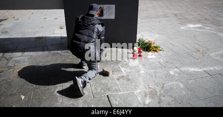 Ein Passant kniet am Tatort von einem tödlichen Messerstecherei in Berlin, Deutschland, 25. August 2014. Die Polizei sucht immer noch der Mann, der tödlich einen 30 Jahre alten Mann in der Nähe des Alexanderplatzes in Berlin Bezirk Mitte am Vortag, 24. August 2014 erstochen. Das Opfer, zusammen mit einem anderen Mann und zwei Frauen war, wurde ohne ersichtlichen Grund angegriffen und starb auf dem Weg ins Krankenhaus. Foto: Jörg Carstensen/dpa Stockfoto