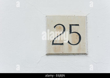 Hausnummer 25 auf eine Steinplatte mit einer grünen Wand-Hintergrund Stockfoto