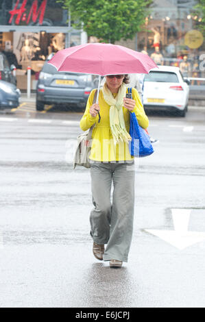 Swansea, Großbritannien. 25. August 2014. Wetter: Eine Frau trägt Cheerfull Farben im Regen - Leute entscheiden, auf einem sehr nassen Bank Holiday Montag Einkaufen in Wales. Bildnachweis: Graham M. Lawrence/Alamy Live-Nachrichten. Stockfoto