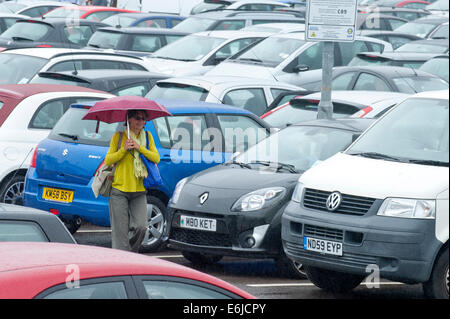 Swansea, Großbritannien. 25. August 2014. Wetter: Eine Frau geht durch eine gepackte Einzelhandel-Parkplatz - Menschen entscheiden, auf einem sehr nassen Bank Holiday Montag Einkaufen in Wales. Bildnachweis: Graham M. Lawrence/Alamy Live-Nachrichten. Stockfoto