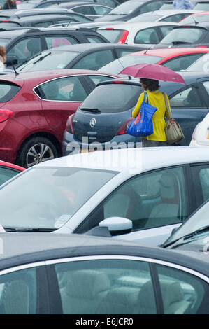 Swansea, Großbritannien. 25. August 2014. Wetter: Eine Frau geht durch eine gepackte Einzelhandel-Parkplatz - Menschen entscheiden, auf einem sehr nassen Bank Holiday Montag Einkaufen in Wales. Bildnachweis: Graham M. Lawrence/Alamy Live-Nachrichten. Stockfoto