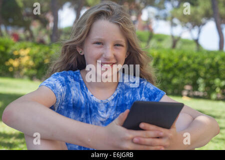 10 Jahre altes Mädchen lesen Ebook lächelnd Stockfoto