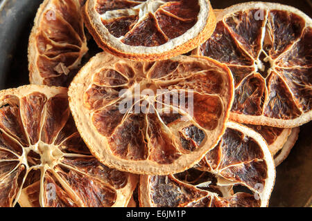 Nahaufnahme von getrockneten Orangenscheiben auf schwarzem Teller Stockfoto