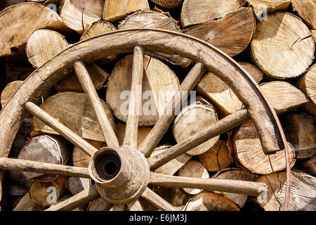 Haufen Brennholz und alte gebrochene Rad irgendwo auf dem Land Stockfoto