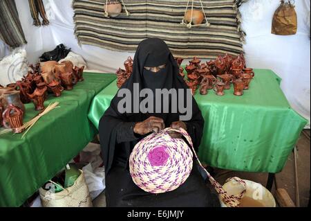 Sanaa, Jemen. 25. August 2014. Während der einwöchigen Sanaa Sommerfest in Sanaa, Jemen, am 25. August 2014 macht eine jemenitische Frau traditionelle handgefertigte Souvenirs. Jemen startete das 7. Sanaa-Sommerfest in der Hauptstadt Sanaa. Die Behörden wollen den Tourismus in dem arabischen Land zu erholen, die politischen Unruhen und tödliche Konflikte seit 2011 gesehen hat. Bildnachweis: Mohammed Mohammed/Xinhua/Alamy Live-Nachrichten Stockfoto