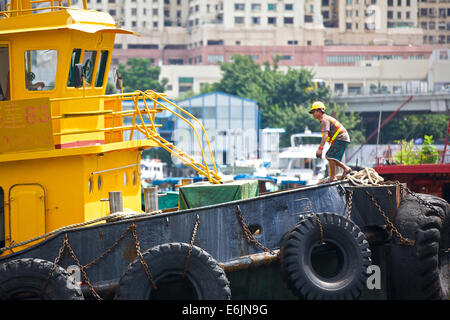 Decksmann Anordnen von Seilen auf einem Schlepper in der Causeway Bay Typhoon Shelter, Hong Kong. Stockfoto