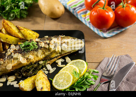 Gebratene Forelle mit Mandeln, Dill und Potato wedges Stockfoto