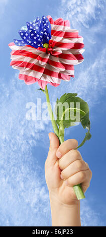 Kinderhand mit USA-Flagge in der Größenordnung von Blume auf Hintergrund des blauen Himmels Stockfoto