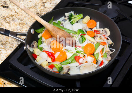 Frische gemischte Gemüse unter Rühren braten mit Zwiebeln, Karotten, Erbsen, Paprika und Sprossen in einer Pfanne Herd simmering. Stockfoto