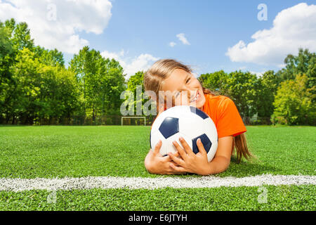 Mädchen hält enge Fußball, lächelnd und Verlegung Stockfoto