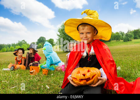 Junge im Assistenten Kostüm hält Halloween-Kürbis Stockfoto