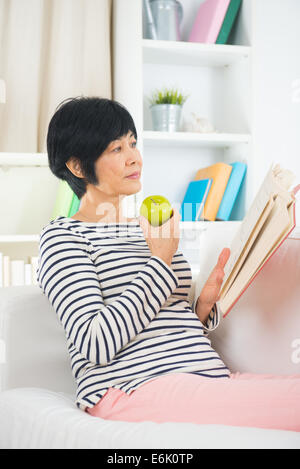 gereifte senior Asiatin lesen auf dem sofa Stockfoto