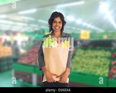 Closeup Portrait, schöne, hübsche junge Frau in Pullover, Abholung, Wahl grünes Blattgemüse in Lebensmittelgeschäft Stockfoto