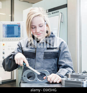 Ein Weibchen schneiden Maschine Operator Trainee ist eine Komponente, Entgraten Schulungszentrum der Motor und Turbine Hersteller Mann Stockfoto