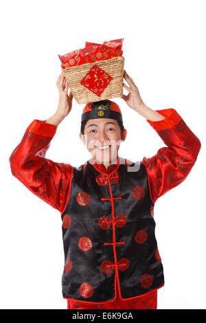 Junger Mann in der chinesischen traditionellen Kleidern mit roten Umschlägen feiert Chinesisches Neujahr Stockfoto