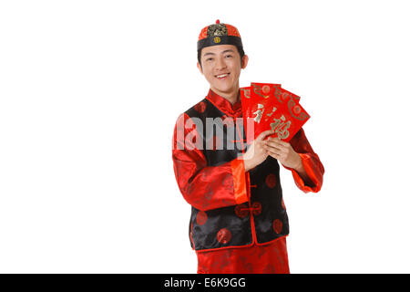 Junger Mann in der chinesischen traditionellen Kleidern mit roten Umschlägen feiert Chinesisches Neujahr Stockfoto