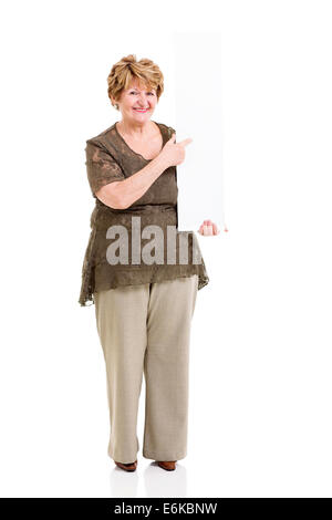 fröhliche ältere Frau zeigt auf leere Tafel isoliert auf weiss Stockfoto