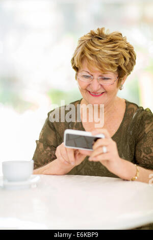 gerne ältere Frau, die e-Mails auf Smartphone zu Hause lesen Stockfoto