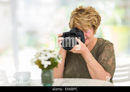ziemlich senior Frau fotografieren Blumen auf dem Tisch Stockfoto