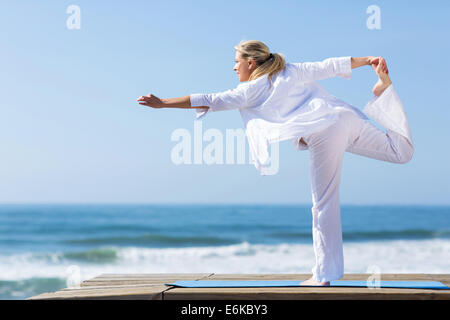Seitenansicht des Reife Frau Yoga pose am Strand Stockfoto
