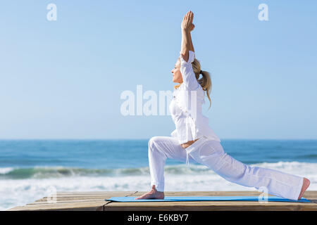 friedliche Mitte Alter Frau Yoga Übung am Strand Stockfoto