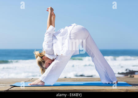 mittlere gealterte Frau Fitness stretching am Strand zu tun Stockfoto