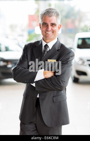 glückliche Mann mittleren Alters arbeiten bei Autohaus Stockfoto