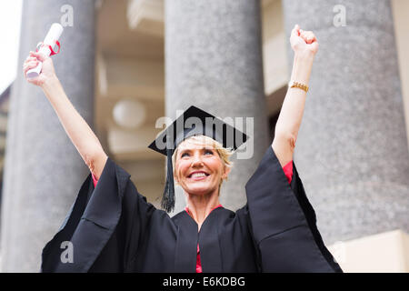 fröhliche weibliche Seniorenuniversität graduate Arme nach oben Stockfoto