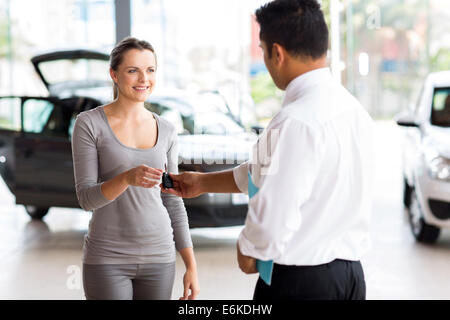 junge Frau, die ihr neues Autoschlüssel vom Verkäufer empfangen Stockfoto