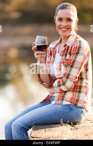 schöne junge Frau Weintrinken auf See Pier im Herbst Stockfoto