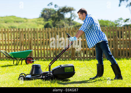 junger Mann Rasenmähen zu Hause Stockfoto