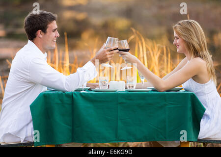 schöne junge Paar beim romantischen Abendessen am See Stockfoto