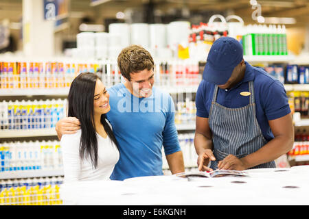 glückliches Paar Malfarbe bei Baumarkt mit Hilfe der Verkäuferin die Wahl Stockfoto