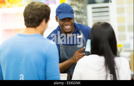 freundliche afrikanische Verkäuferin helfen paar Malfarbe bei Baumarkt wählen Stockfoto