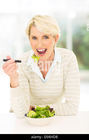 schöne Mitte Alter Frau Salat aus frischen Gemüse zu Hause essen Stockfoto