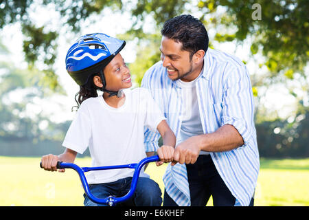 glückliche indische Vater helfen, seine hübsche Tochter Fahrrad fahren Stockfoto