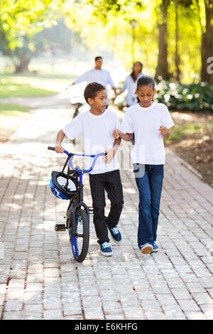 Kinder mit dem Fahrrad mit Eltern hinter im park Stockfoto