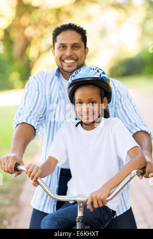 glücklich indischer Vater und Tochter im Freien auf einem Fahrrad Stockfoto