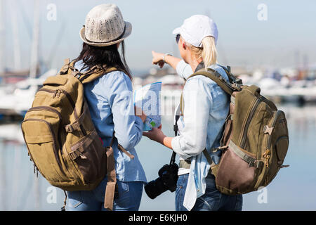 Rückansicht der zwei weibliche Touristen durch den Hafen und deutete auf Distanz Stockfoto