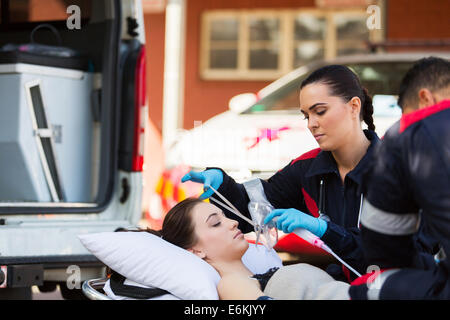 junge weibliche EMT bewusstlosen Patienten Sauerstoffmaske aufsetzen Stockfoto