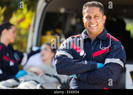 gut aussehend Sanitäter vor Patienten und Kollegen Stockfoto