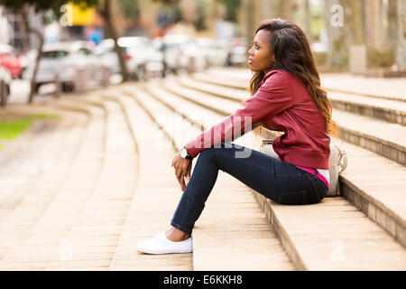 nachdenkliche junge afrikanische Frau sitzen im freien Stockfoto