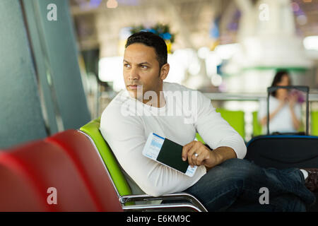 nachdenklicher Mann sitzt am Flughafen warten auf seiner Flucht Stockfoto