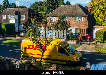 Parkef DHL-Lieferwagen, mit dem Fahrer ein Briefträger außerhalb eines 1930er Jahre Einfamilienhaus in Banstead, Surrey, England, UK zu plaudern. Stockfoto